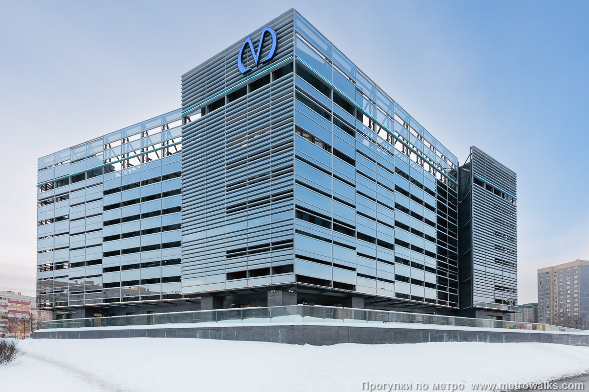 Фотография станции Юго-Западная (Красносельско-Калининская линия, Санкт-Петербург). Тот же вестибюль, вид сзади. Отсутствие многих фасадных панелей придаёт облику здания специфический вид “открытости всем ветрам” и оно визуально напоминает многоуровневый паркинг.